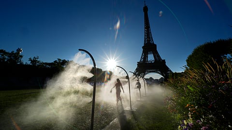 A spectator walks through a water mist sprayers on her way to Eiffel Tower Stadium to watch a beach volleyball at the 2024 Summer Olympics, Sunday, July 28, 2024, in Paris, France. 