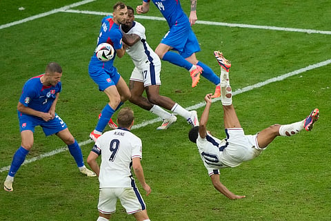 England's Jude Bellingham, right, scores his side's first goal with an overhead kick during a round of sixteen match between England and Slovakia at the Euro 2024 soccer tournament on June 30, 2024. 