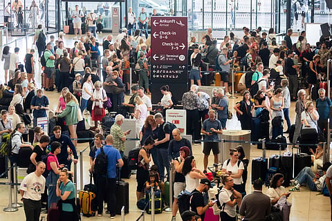 Passengers wait in front of check-in counters at the capital's Berlin Brandenburg Airport, in Schönefeld, Germany, Friday July 19, 2024, after a widespread technology outage disrupted flights, banks, media outlets and companies around the world. 