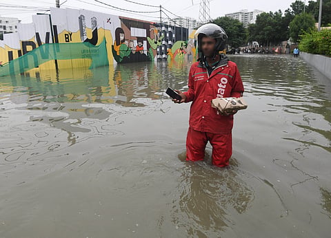A food delivery person wades through a flooded street in Hyderabad.