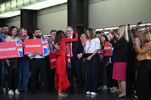 Britain's Labour Party leader Keir Starmer (C) is hugged as he arrives with his wife Victoria (C-R) to deliver a speech during a victory rally at the Tate Modern in London early on July 5, 2024. 