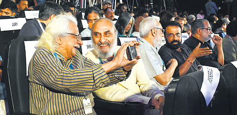 Filmmaker Adoor Gopalakrishnan shows a picture clicked by him to documentary filmmaker Rajesh Bedi at the opening ceremony of the 16th edition of the IDSFFK in Thiruvananthapuram.