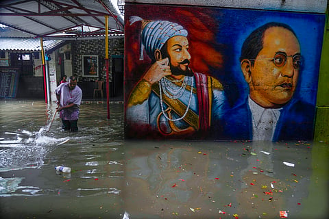 An employee tries to clear waterlogging at a school compound after a heavy rainfall in Mumbai.