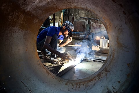 A welder welds a machine inside the rolling and fabrication factory