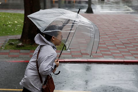 A woman struggles with her umbrella against gusts of wind generated by Typhoon Gaemi in Taipei, Taiwan