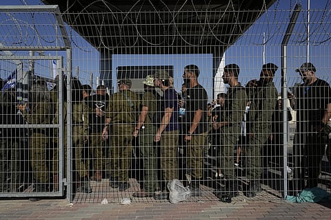 Israeli soldiers gather at the gate of the Sde Teiman military base, as people protest in support of soldiers being questioned for detainee abuse, Monday, July 29, 2024.