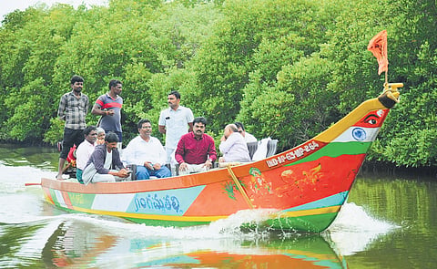 Bapatla district Collector J Venkata Murali travelling in a motorised boat from Suryalanka Adarshnagar Bridge to Nizampatnam harbour 