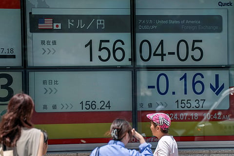Pedestrians walk past an electronic board　displaying the exchange rate for the Japanese yen against the US dollar in Tokyo on July 18, 2024. 
