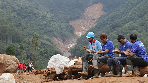 A group of rescue volunteers takes a break at Punchirimattam, the landslide-hit area in Kerala's Wayanad district.