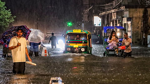 People wade through a waterlogged road during rain at Jangpura area, in New Delhi.