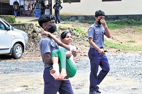 Boy scout Abhinav carries Shahana, who injured her legs in the landslide, for medical check-up at the relief camp opened at 
SDM LP School, Kalpetta, Wayanad, on Tuesday