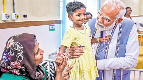 Prime Minister Narendra Modi interacts with a child affected by the landslide, at a hospital in Wayanad on Saturday