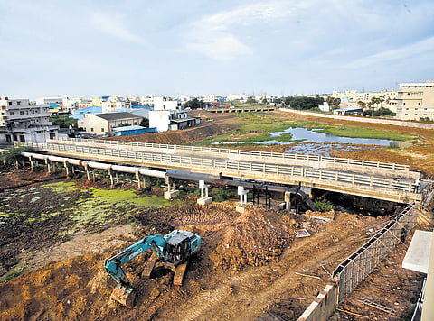 Construction of the Vadaperumbakkam bridge at an estimated cost of `22.41 crore is being dragged out by legal disputes over the acquisition of 13 land plots 