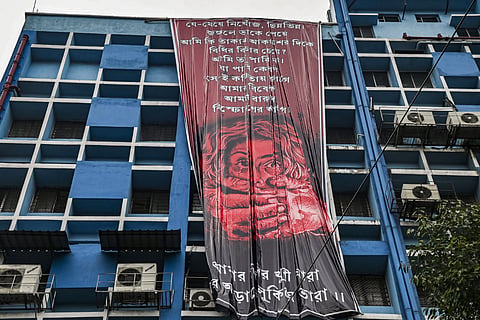 Junior doctors hang a giant poster from the roof of the R G Kar College and Hospital during their protest against alleged rape and murder of a woman trainee doctor of the hospital, in Kolkata, Tuesday, Aug. 20, 2024.