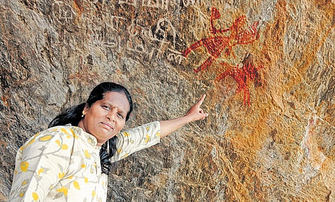  P Devi Arivuchelvam pointing 
to a rock art 