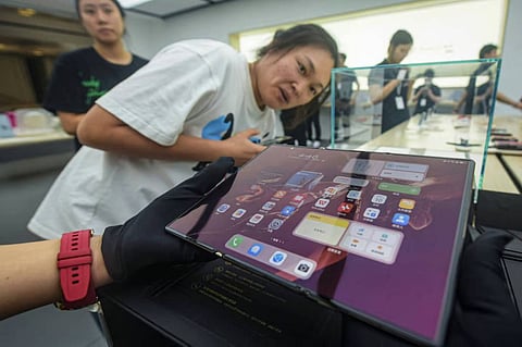A visitor checks out the fully opened display of the Mate XT, Huawei Technologies’ new tri-fold smartphone, at a Huawei store in Hangzhou, capital of eastern Zhejiang province, on Tuesday. 