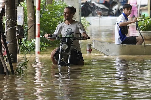 A man pushes his motorbike in a flooded street in the aftermath of Typhoon Yagi, in Hanoi, Vietnam on Thursday, Sept. 12, 2024. 