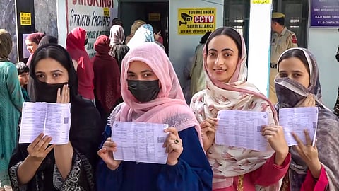 Women voters show their voting slips at a women-only polling station during the first phase of Jammu and Kashmir Assembly elections, in Kishtwar district.