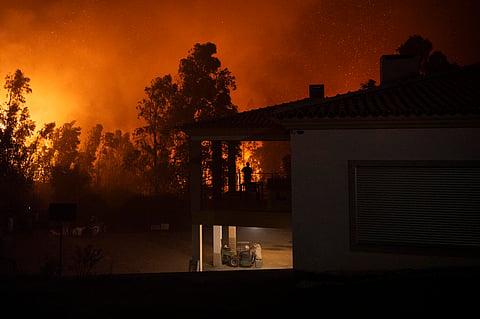 A silhouette of a woman watching a wildfire is pictured as it approaches Veiga village in Agueda, Aveiro on September 17, 2024. 