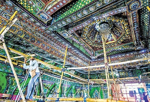 Workers fixing decorative panels made of colourful glasses at Bomikhal Durga Puja pandal in Bhubaneswar 