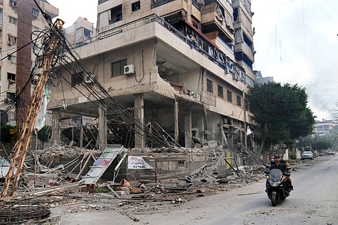 Lebanese men ride a scooter past a damaged building hit by an Israeli airstrike in Dahiyeh, Beirut, Lebanon, Monday, Oct. 7, 2024. 