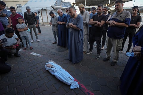 Mourners pray over the body of a Palestinian child, Hosam Al Khaldi, killed in the Israeli bombardment of the Gaza Strip outside the hospital morgue in Deir al-Balah on Wednesday, Oct. 9, 2024. 
