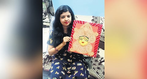 Snigdha holding her artwork made using paddy grains