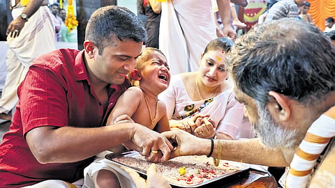 Attukal Devi Temple head priest V Muraleedharan Namboothiri introduces a child to the world of letters during the Vijayadashami celebrations at the temple 
on Sunday.