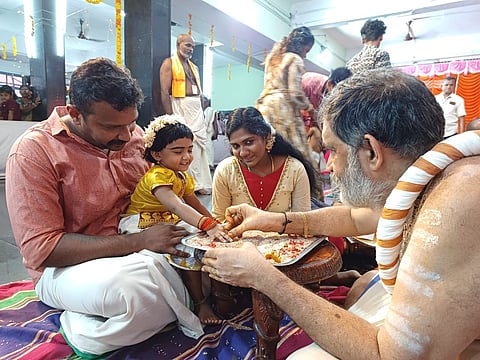 Attukal Devi Temple head priest V Muraleedharan Namboothiri introducing a kid to the world of letters on the occasion of Vijayadashami day at temple premises on Sunday.