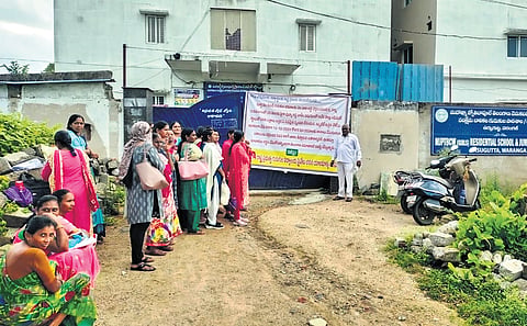 Teachers wait outside a residential school building in Warangal district on Tuesday. The building gate was locked by the owner demanding payment of rent arrears 