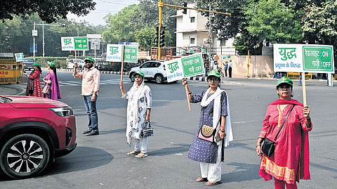 Volunteers hold placards at ITO to inspire citizens to put off their car engines while waiting at the traffic signal, in New Delhi on Monday. 