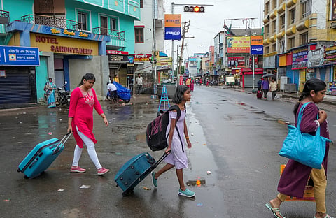 People with their luggage leave coastal areas ahead of the landfall of Cyclone 'Dana'