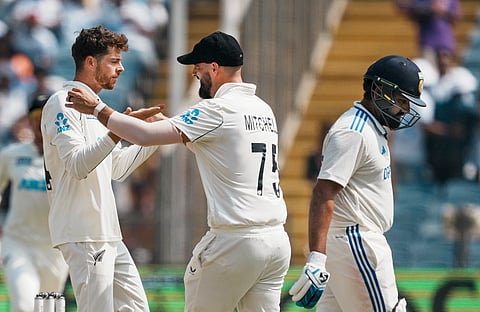 New Zealand's Mitchell Santner celebrates with Daryl Mitchell after taking the wicket of Rohit Sharma on the third day of the second test cricket match between India and New Zealand.