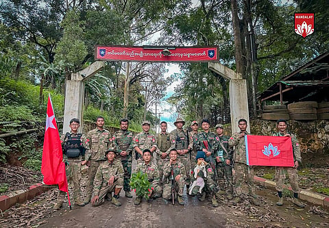 In this photo provided by Mandalay People's Defence Force, its members pose for a photograph in front of the gate of the captured army battalion in Mogok township in Mandalay region, Myanmar, on July 25, 2024. 