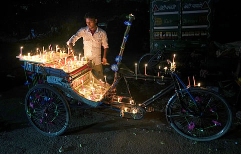 A rickshaw puller lights candles on his rickshaw during the Diwali festival, at Rani Garden, Shastri Nagar, in East Delhi, Thursday, Oct. 31, 2024. 