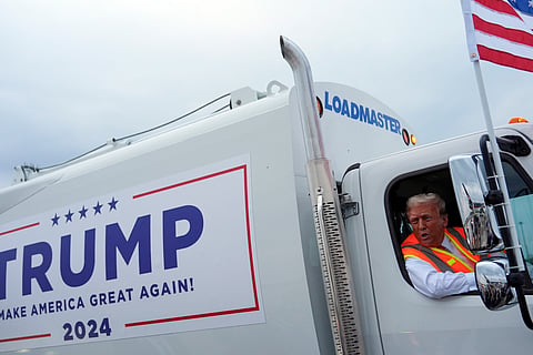 Republican presidential nominee former President Donald Trump talks to reporters as he sits in a garbage truck Wednesday