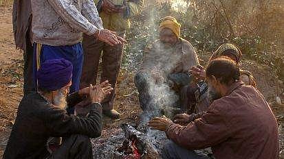 People keep themselves warm around a bonfire during a cold winter morning 