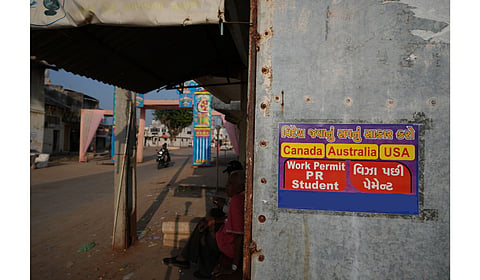 An advertising poster pasted on a shop at Dingucha village in Gandhinagar, India, Tuesday, Nov. 12, 2024. Poster reads in Gujarati "Make your dream of going abroad come true", on top and "Payment after visa". 