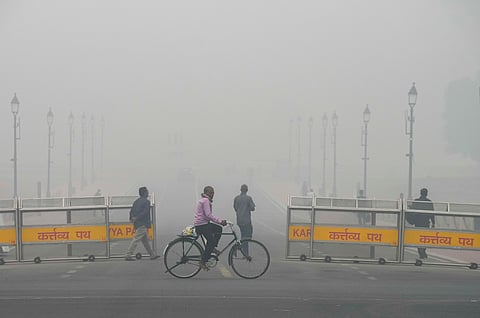 A man cycles near the India Gate amid low visibility due to smog as air quality remains in 'severe' category, in New Delhi