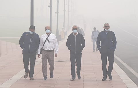 People walking through the streets of Delhi wearing masks amid heavy smog. 