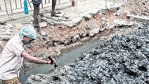 workers manually clearing silt from sewage-contaminated water