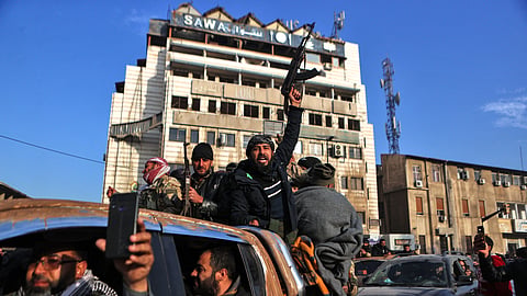 Syrian rebel fighters celebrate near the Clock Tower in Homs on December 8, 2024, after rebel forces entered Syria's third city overnight. 