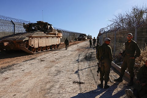 Israeli soldiers stand on the fence with the buffer zone that separates the Israeli-annexed Golan Heights from Syria, on December 9, 2024, near the Druze village of Majdal Shams