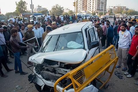 People stand near a damaged vehicle after a taxi collided with Rajasthan CM Bhajan Lal Sharma's convoy at Akshay Patra crossing in Jaipur, Wednesday, Dec. 11, 2024.