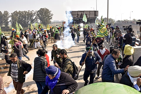 Farmers move away as security personnel fire teargas shells to disperse them during their agitation at the Shambhu border, in Patiala district, Punjab, Saturday, Dec. 14, 2024. 
