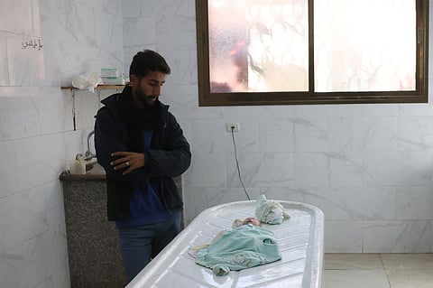 A Palestinian man looks at the body of his niece three-week old Sila al-Faseeh, who reportedly died of hypothermia, as it lies in the morgue of the Nasser Hospital in Khan Yunis in the southern Gaza Strip on December 25, 2024, amid Israel's ongoing war on Gaza. 