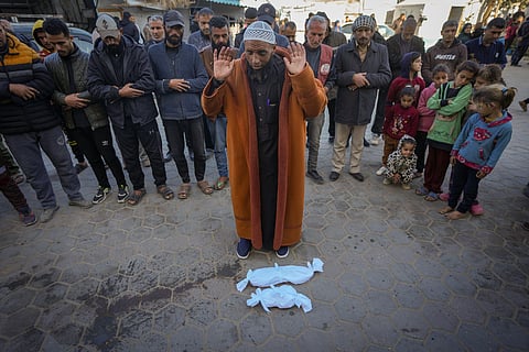 Imam Islam Abu Suaied prays over the bodies of two babies before their burial at the Al-Aqsa Martyrs Hospital in Deir al-Balah, central Gaza Strip, Sunday, Dec. 29, 2024. 