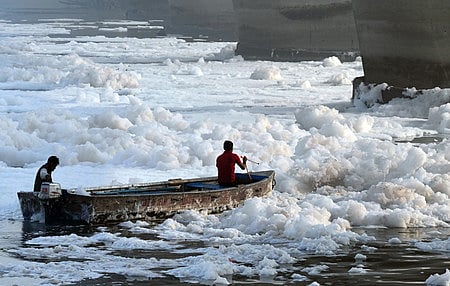 Workers spray chemicals to dissolve toxic foam in the polluted Yamuna river at Kalindi Kunj during 'Chhath'' festival, in New Delhi, 2024. 