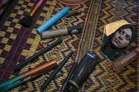 Alaa Hamami gazes into a fragment of a broken mirror as she poses for a portrait beside her deteriorating cosmetics in her tent at a camp for displaced Palestinians in Deir al-Balah, Gaza Strip, Dec. 18, 2024.