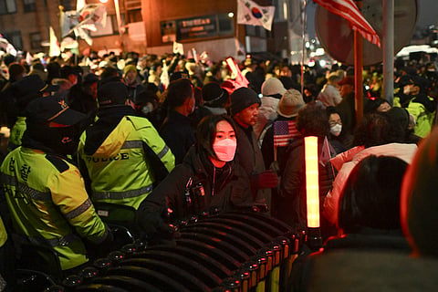 Policemen stand guard in front of people taking part in a rally to support South Korea's impeached president Yoon Suk Yeol near the presidential residence in Seoul on Thursday. 
